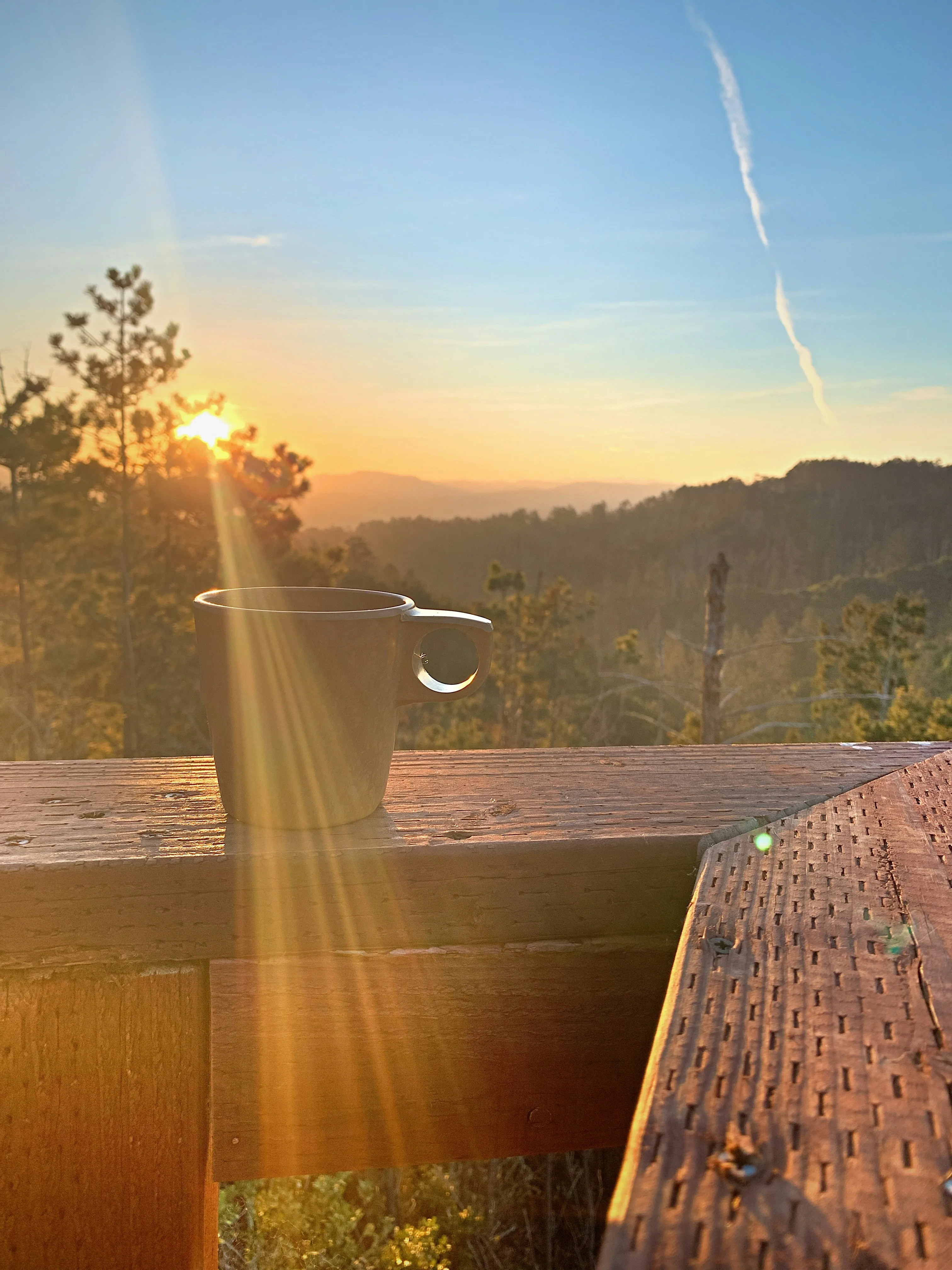 A cup of coffee resting on a wooden table.